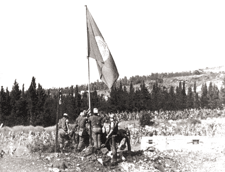 Les troupes de la FINUL hissant pour la première fois le drapeau de l'ONU à Nakoura au Sud Liban en mars 1978.  Source Archives ONU