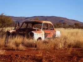 photo of corroded vintage white and red sedan on brown grass