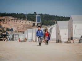 ethnic kids walking on road in refugee camp