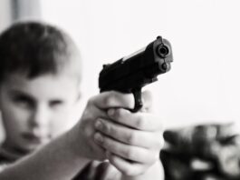 grayscale photo of a boy aiming toy gun selective focus photography