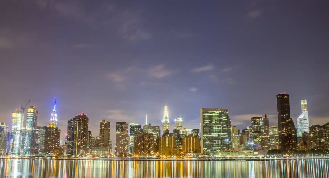 city skyline across body of water during night time