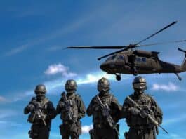 four soldiers carrying rifles near helicopter under blue sky