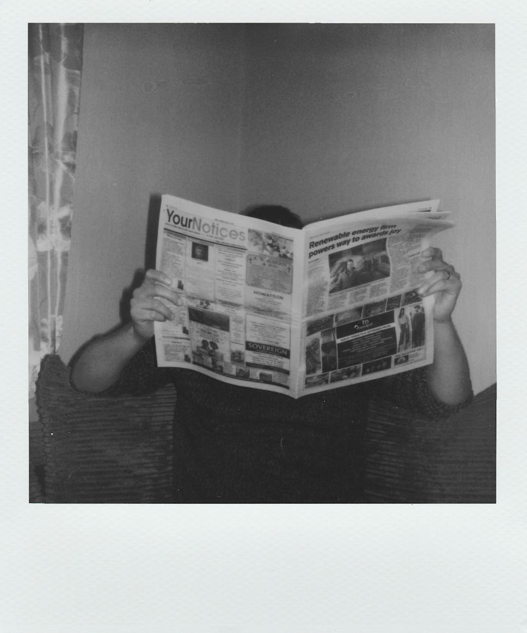grayscale photography of man reading newspaper