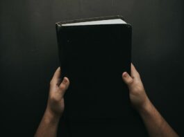 person holding black cover bible