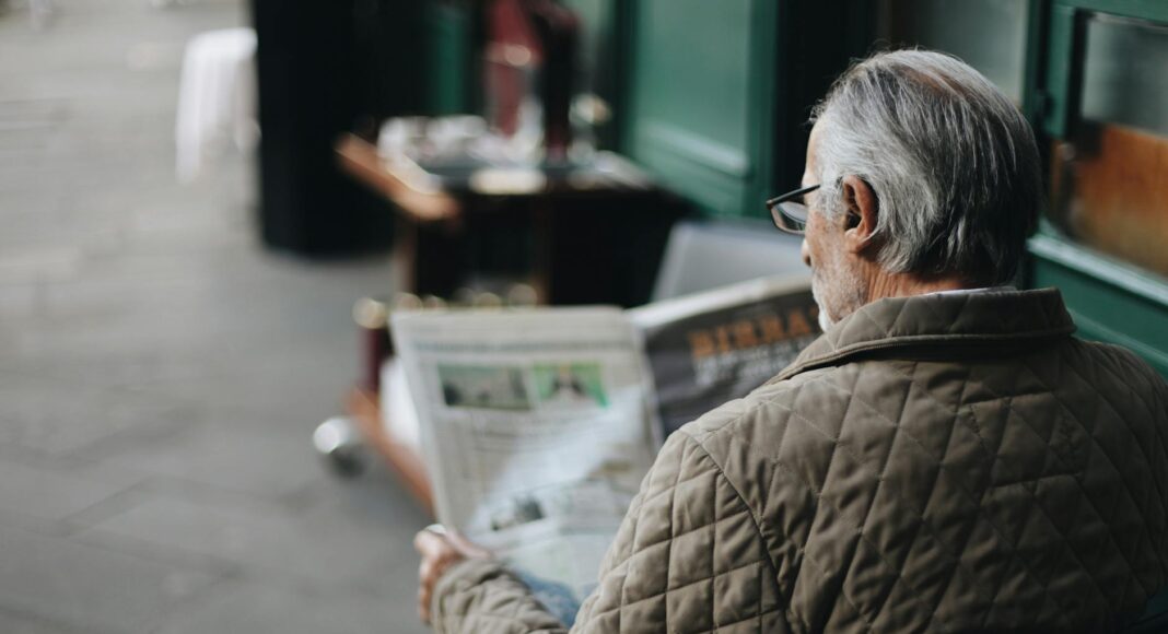 man sitting reading newspaper