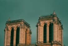 a large building with a clock on it with Notre Dame de Paris in the background