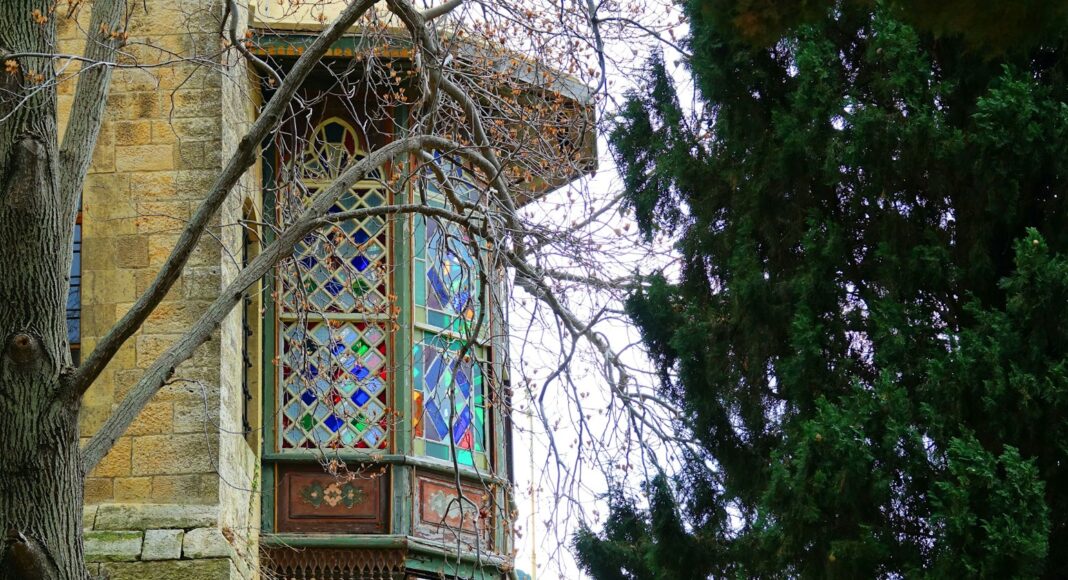 a building with a stained glass window and a tree in front of it