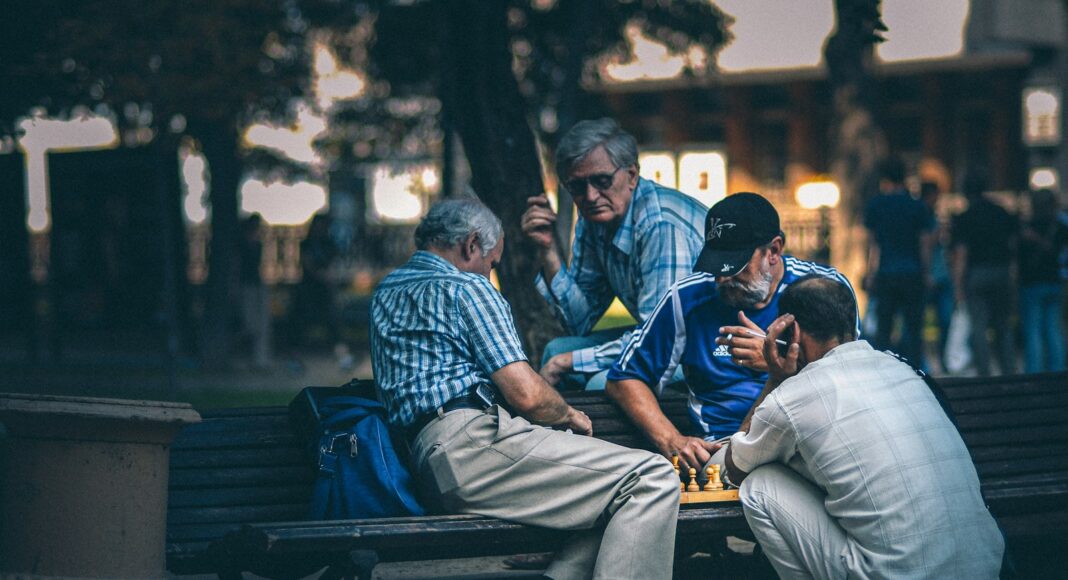 man in blue and white plaid dress shirt sitting on bench