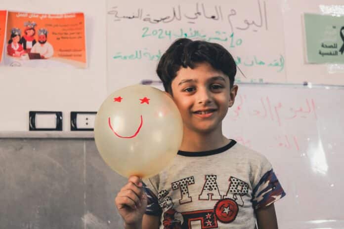 A young boy holding a balloon with a smiley face on it
