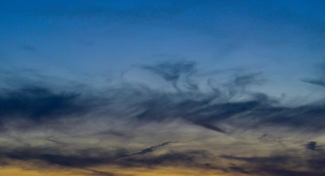 A plane flying in the sky at sunset