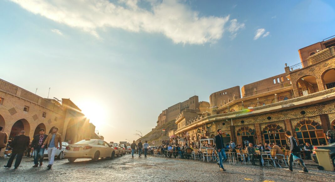 people walking on beach near brown concrete building during daytime